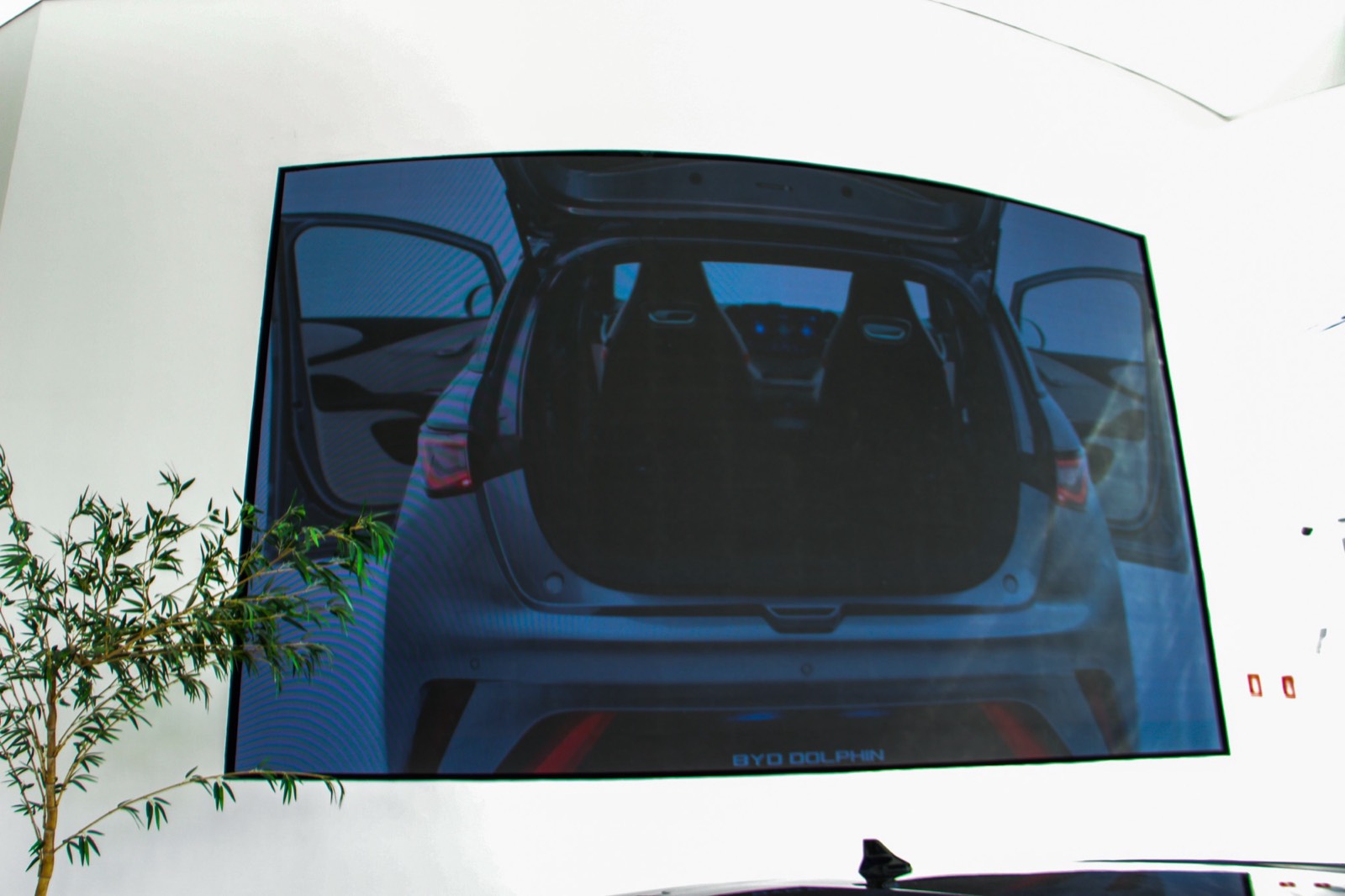 Painel de LED indoor exibindo o porta-malas aberto de um carro, no showroom da BYD
