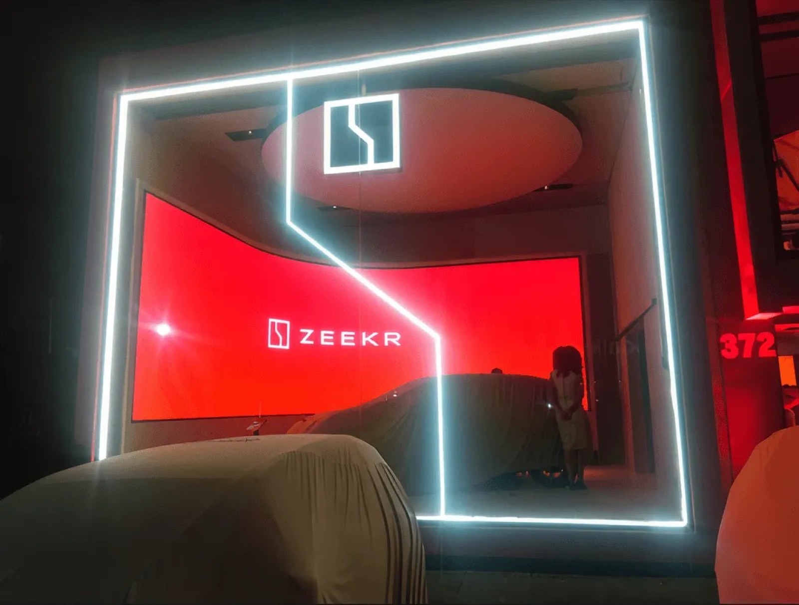 Painel de LED indoor com a marca ZEEKR e moldura de luz branca, em ambiente escuro do showroom