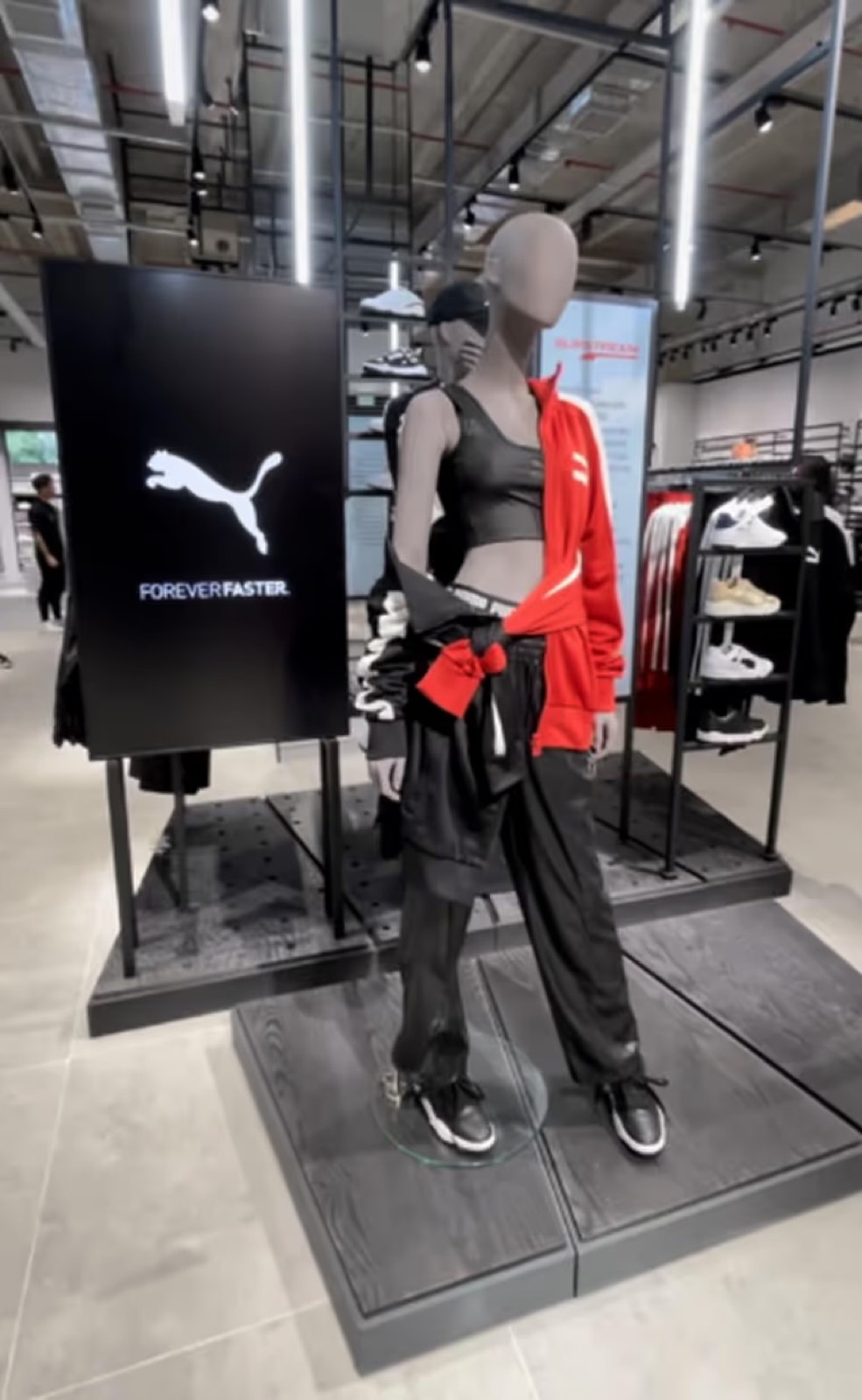 Display com o logotipo Puma ao lado de um manequim com roupas esportivas, dentro da loja
