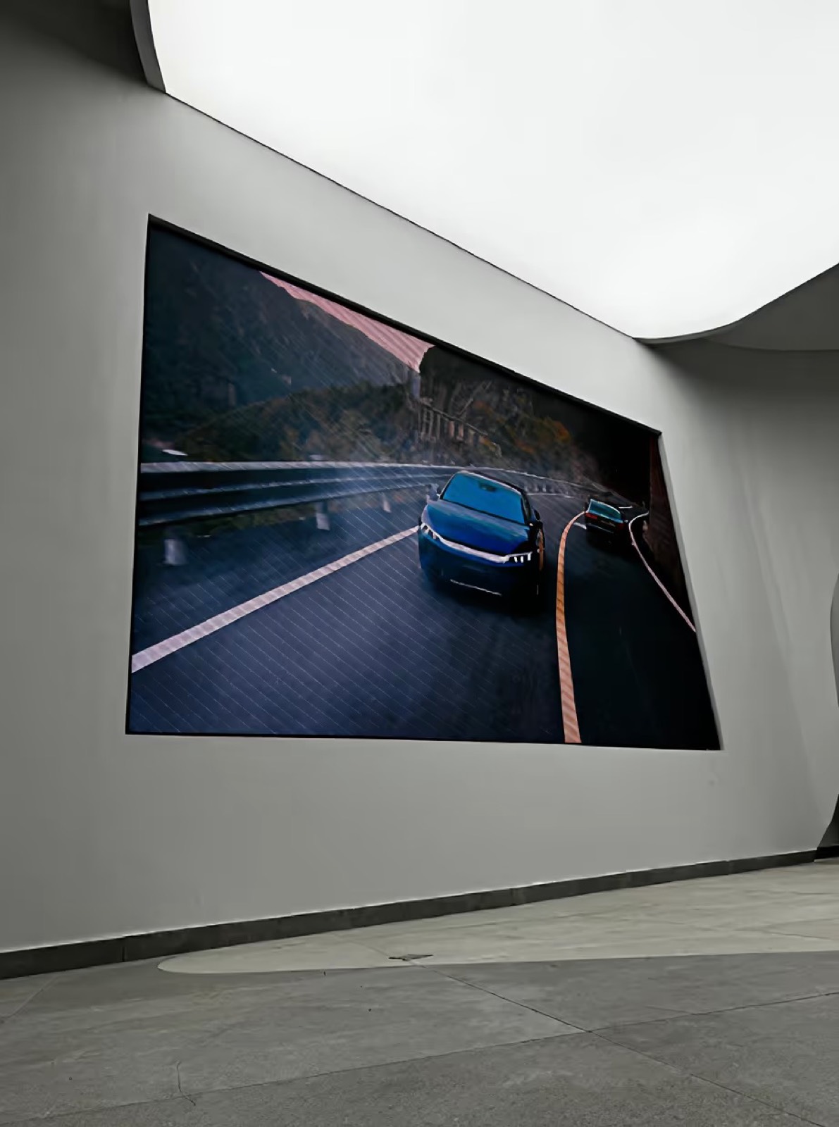 Painel de LED indoor na parede exibindo a imagem de um carro em uma estrada