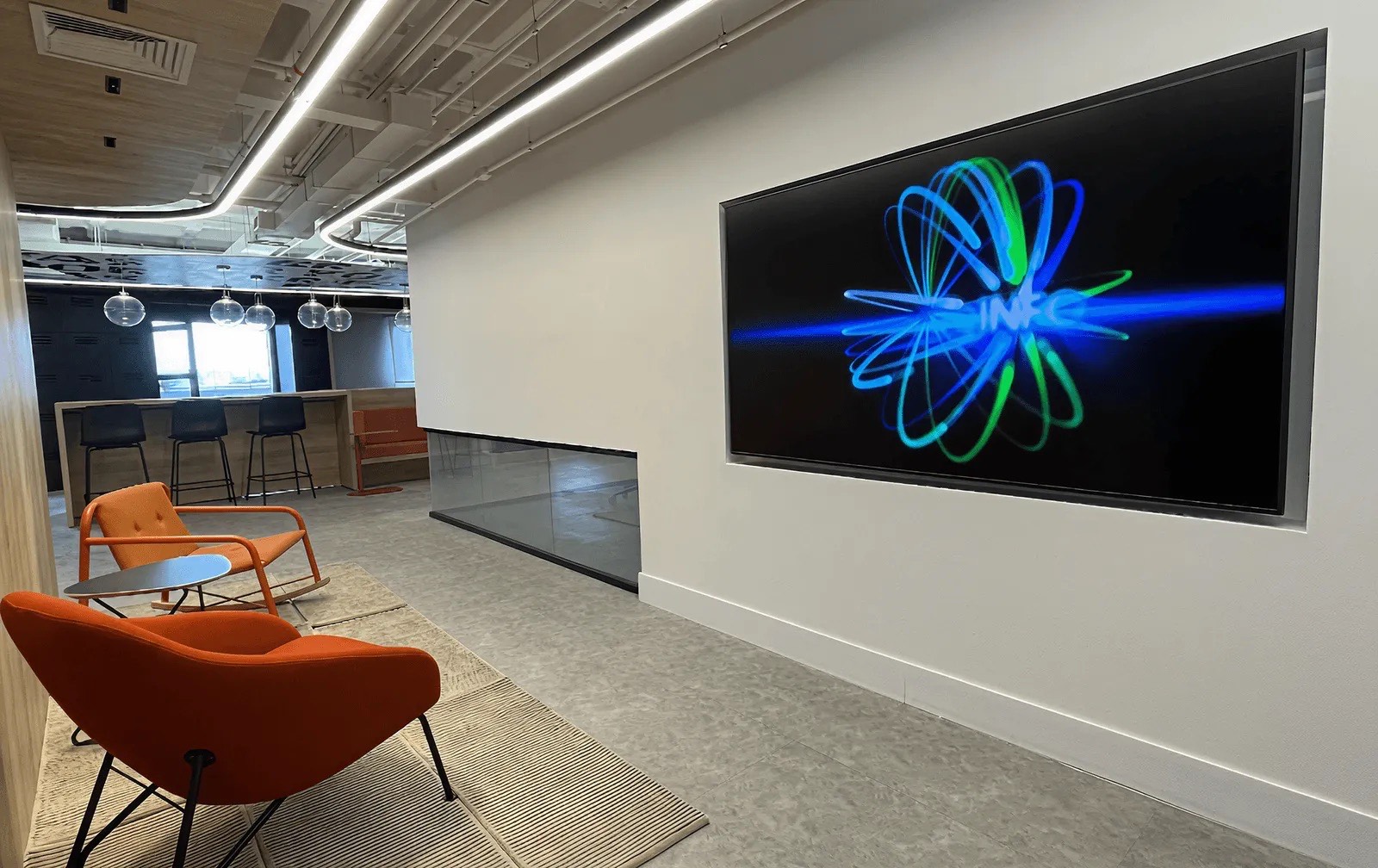 Painel de LED na parede de uma recepção com poltronas, exibindo uma arte azul