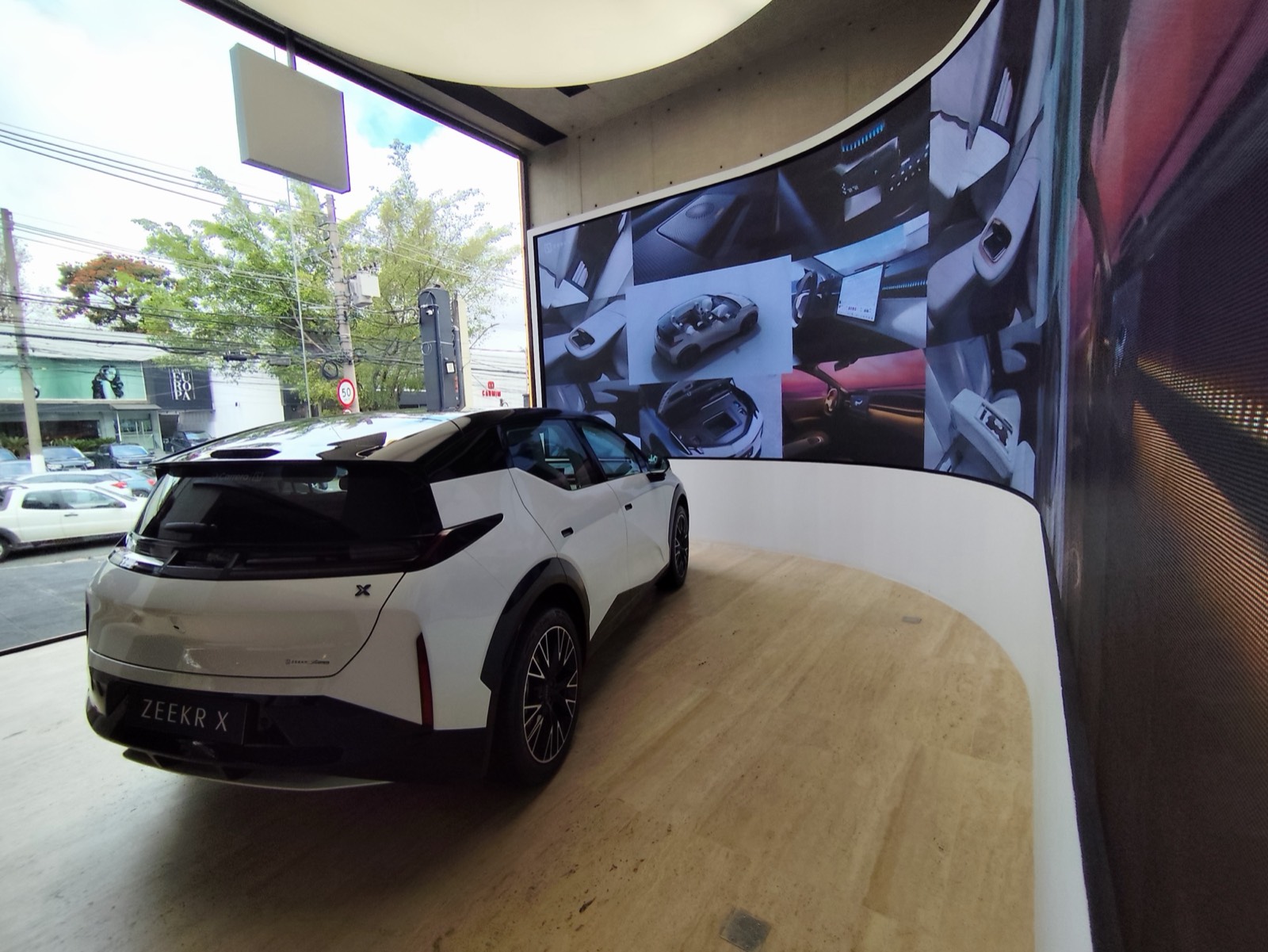 Painel de LED curvo ao lado de um carro em showroom