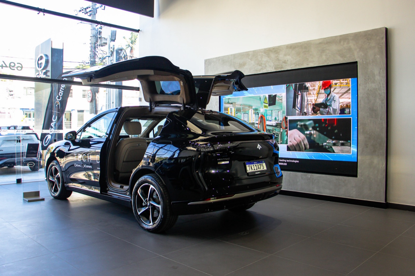 Painel de LED na parede de uma concessionária, atrás de um carro preto